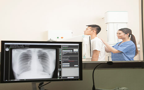 Female Doctor Examining Male Patient’s Mid Section With X-ray Machine